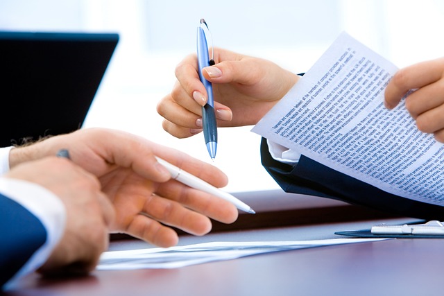 Duas pessoas a rever um contrato de empréstimo impresso à mesa com uma caneta